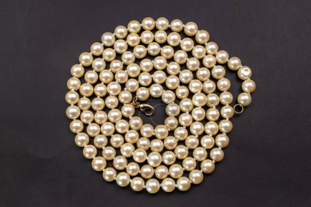 Pearl necklace on black background. Flat lay, top view.