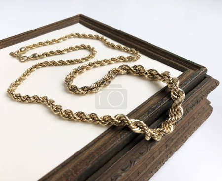 Gold chain in a wooden box on a white background, close-up