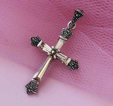 Cross on the background of a pink veil. Christian symbol of faith