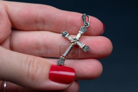 Cross in the hands of a woman. Close-up. Dark background.