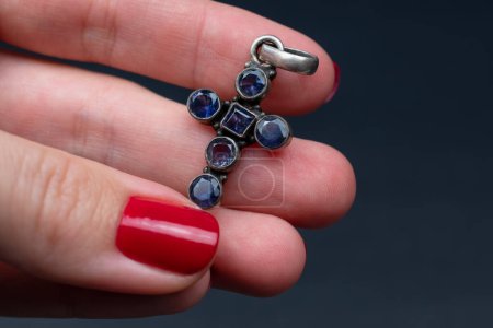 Female hand with red manicure holding a silver ring with blue stones