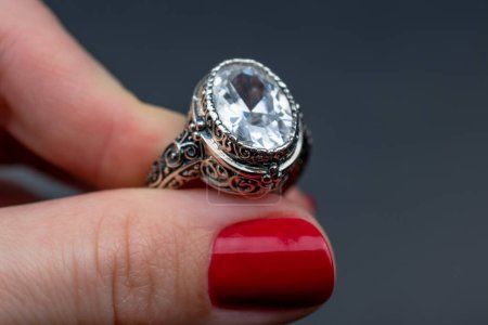 Foto de Anillo de joyería con diamante en mano femenina sobre fondo oscuro. - Imagen libre de derechos