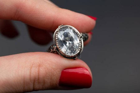 Jewelry ring in the hand of a woman on a gray background