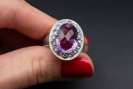 Téléchargez les photos : Main féminine avec une belle manucure tenant un anneau de saphir violet. - en image libre de droit