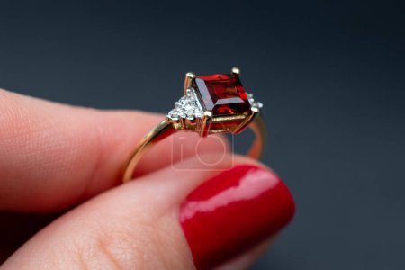 Téléchargez les photos : Bague de mariage avec diamant rouge à la main sur fond sombre. - en image libre de droit