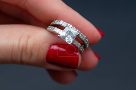 Téléchargez les photos : Bague de mariage avec diamant à la main sur un fond sombre. - en image libre de droit