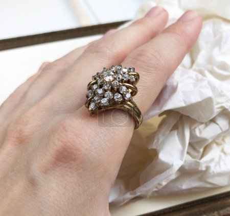 Diamond ring on a female hand with crumpled paper in the background