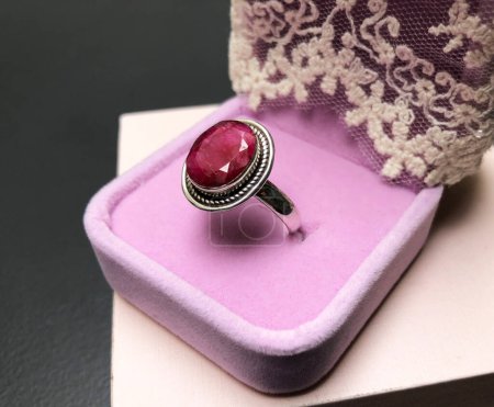 jewelry ring with red ruby in purple box on black background
