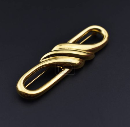golden brooch on black background, closeup photo with shallow depth of field