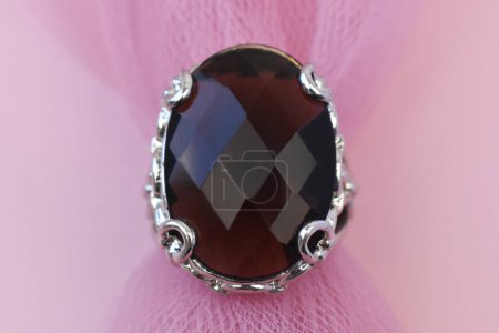 Jewelry ring with gemstone on a pink fabric background.