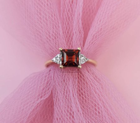 Jewelry diamond ring on pink tulle background, top view