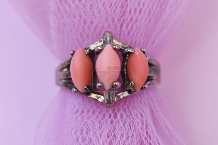 Jewelry ring with pink stones on a pink background close up