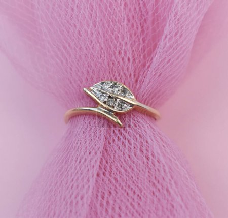 Jewelry diamond ring on a pink fabric background close-up