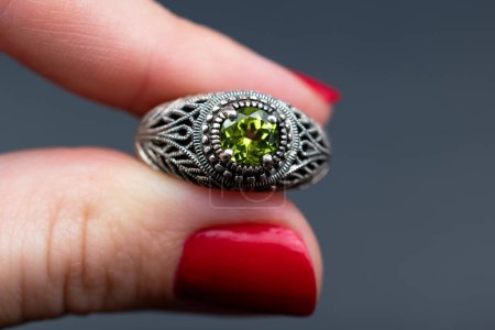 Jewelry ring with green gemstone on a female finger.