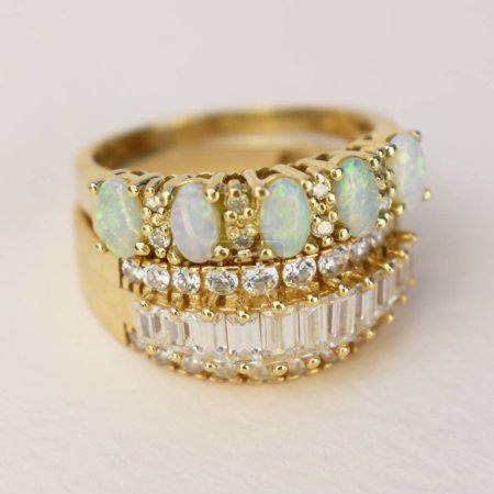Close up of gold ring with green gemstone on white background.