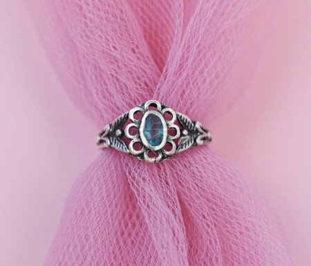 Jewelry ring with blue gemstone on a pink fabric background