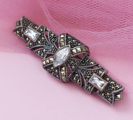 broche de joyería con diamantes sobre fondo rosa de cerca