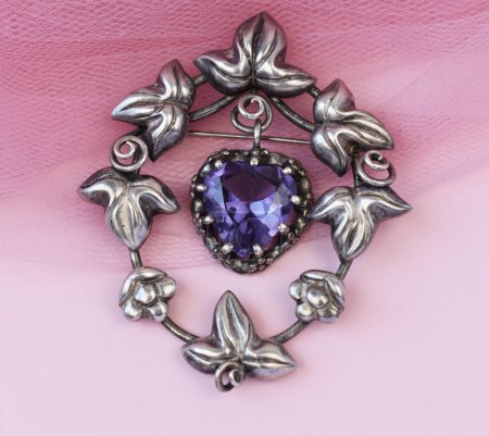 Beautiful brooch with amethyst on a pink background close up