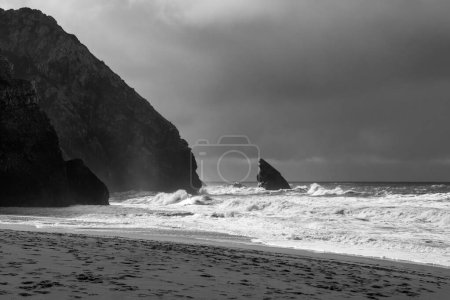 Black and white photo of a stormy sea and a rocky beach
