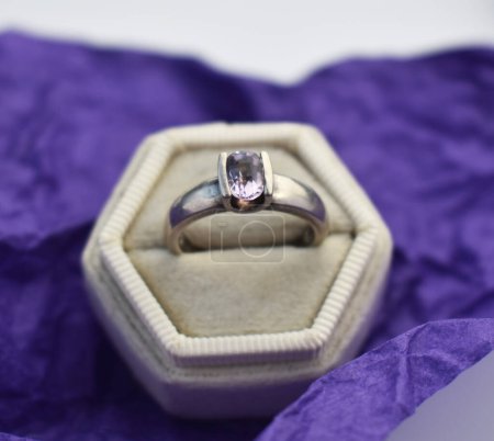Wedding rings in a box on a purple cloth background.