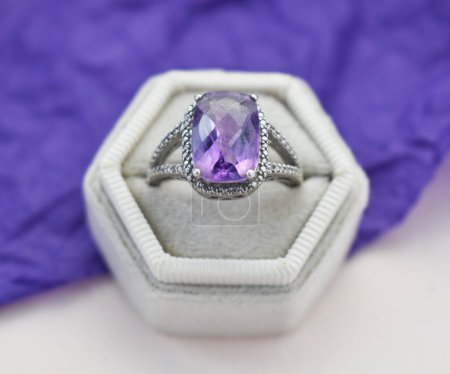 Jewelry ring with amethyst in a box on a purple background