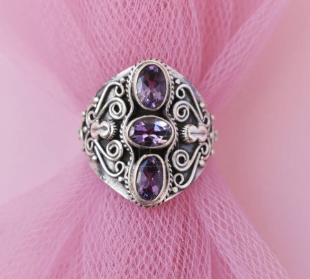 Jewelry ring with precious stones on a pink background close up