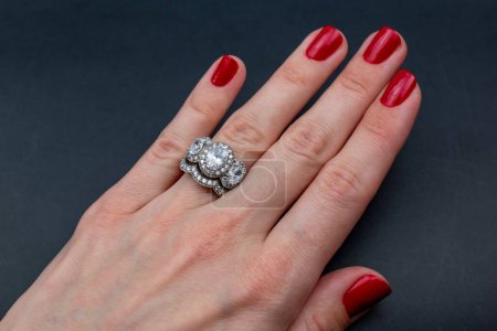 Diamantring an der Hand einer Frau auf dunklem Hintergrund. Nahaufnahme.