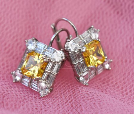 jewelry earrings with diamonds on a pink background close up