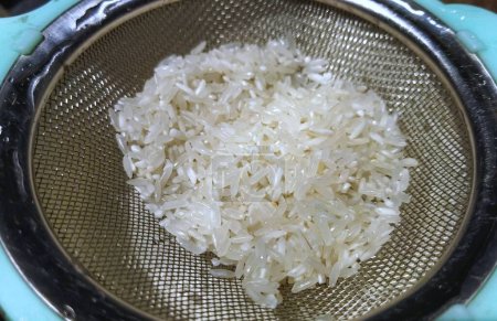 Téléchargez les photos : Riz blanc lavé sur un tamis de cuisine - en image libre de droit