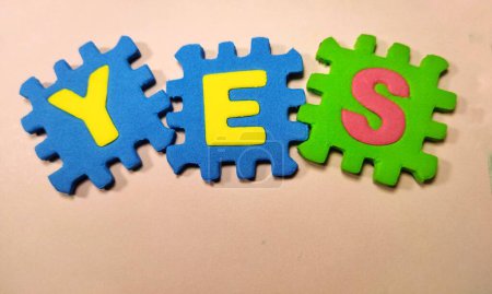 Writing the words 'YES', displayed with puzzle letters, isolated on light oranges background