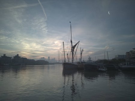Photo for Dawn over River Thames (2). Sailing barge with London docklands in distance. Landscape format. - Royalty Free Image