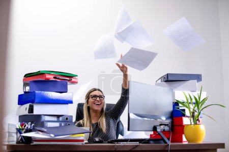 Businesswoman throws papers in office with a big smile on her face