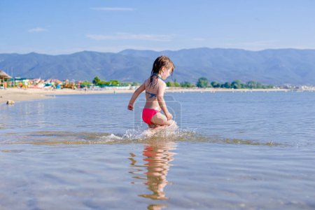 Photo for Baby girl is walking into the sea - Royalty Free Image
