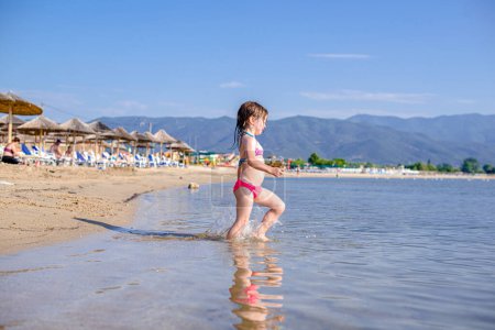 Photo for Little girl is entering the sea - Royalty Free Image
