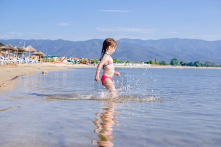 Photo for Little girl is walking into the sea - Royalty Free Image
