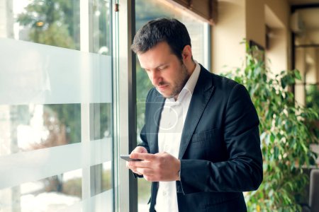 Young businessman is standing next to window