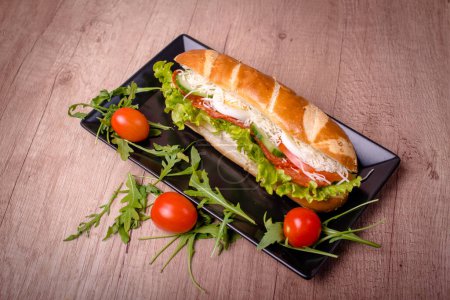 Nice decorated plate with delicious sandwich on the wooden table