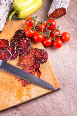 Cutting knife and meat delicatessen on a wooden board, high angle view