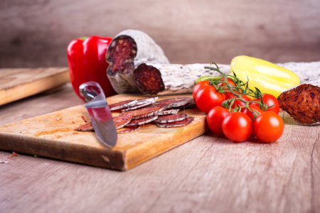 Cutting knife and meat delicatessen on a wooden board