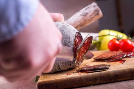 Téléchargez les photos : L'homme coupe de la viande fumée, tranchant délicatesse - en image libre de droit