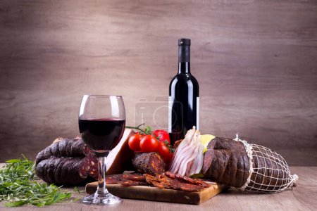 Red wine and delicatessen, on a rustic background