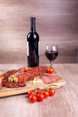 Wine and food, red wine, tomato, olives, paprika and smoked meat delicatessen