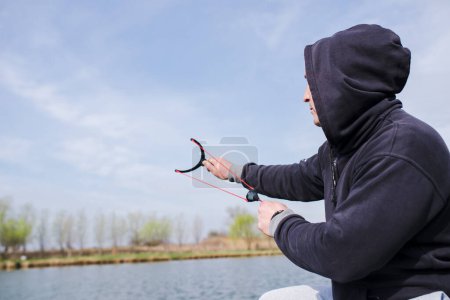 Photo for Man feeding fish with slingshot on lake - Royalty Free Image