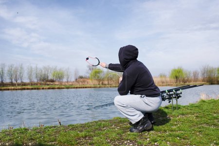 Photo for Man feeding fish with slingshot - Royalty Free Image