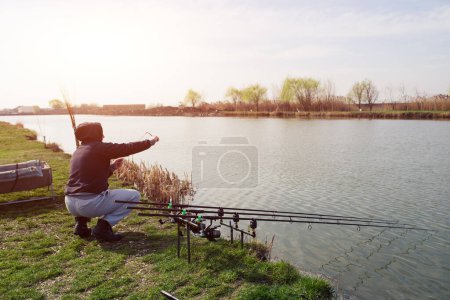 Photo for Man is feeding fishes on lake - Royalty Free Image