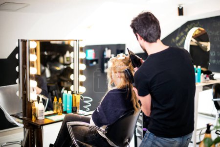 Téléchargez les photos : Nouvelle coiffure pour fille blonde, par jeune coiffeur attrayant - en image libre de droit