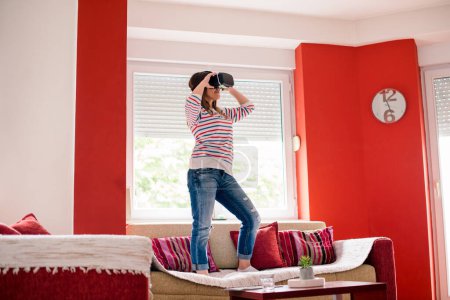 Junge Frau nutzt VR-Brille im Wohnzimmer