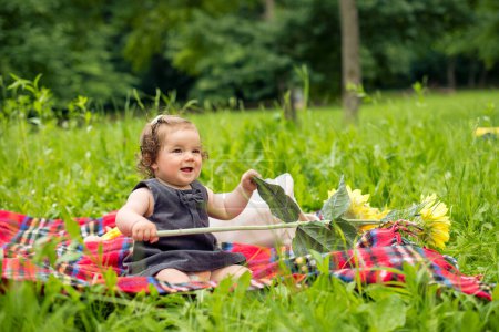 Bébé fille joue avec tournesol sur pique-nique