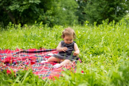 Bébé jouant dans la nature sur couverture à carreaux