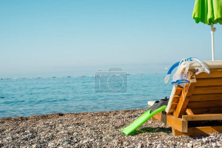 Pebble beach paradise, diving equipment on a wooden chair